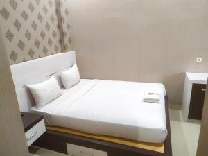 北干巴鲁RedDoorz Syariah near Sultan Syarif Kasim II Airport的白色床单和枕头的酒店客房内的白色床