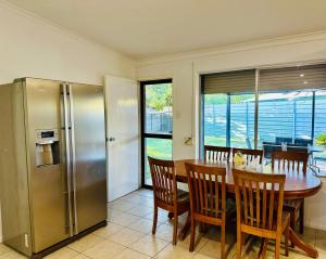 艾利斯斯普林斯Grabber- Three bedroom charm in Alice Springs的厨房配有桌子和不锈钢冰箱。