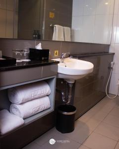 万隆Ivory Hotel Bandung的浴室配有盥洗盆、镜子和毛巾