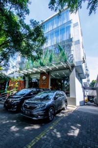 万隆Ivory Hotel Bandung的两辆汽车停在大楼前