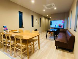 福冈SYA Hotel-上呉服町 一軒家貸し切り的一间带桌子、沙发和电视的用餐室