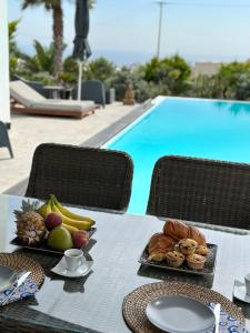 弗通Kaminos Private Villa的一张桌子,上面有食物,放在游泳池边