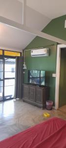达叻府บ้านลูกจัน Bann Lookjan Trat的客厅设有一台平面电视,位于绿色的墙壁上