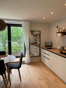 ĶesterciemsSeaside apartment Albatross, 16的厨房配有白色橱柜、桌子和窗户。