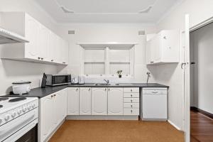悉尼Signature Queen Room in Auburn的白色的厨房配有白色的橱柜和微波炉