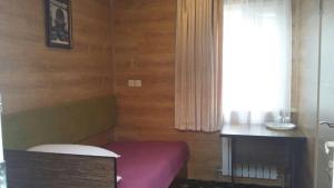 奇姆肯特Sapar Budget Hotel的客房设有紫色的床、桌子和窗户。