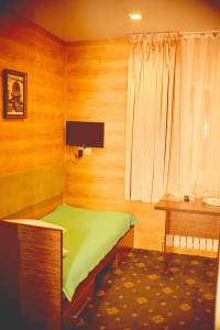 奇姆肯特Sapar Budget Hotel的一间小卧室,配有绿色的床和一张书桌