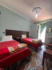 艾兹鲁Hotel des cedres,azrou maroc的酒店客房,配有两张带红色床单的床