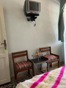 艾兹鲁Hotel des cedres,azrou maroc的一间设有两把椅子、一张桌子和一台电视的房间