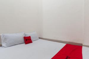 棉兰RedDoorz near UISU teladan Medan的一张带白色枕头和红色毯子的床
