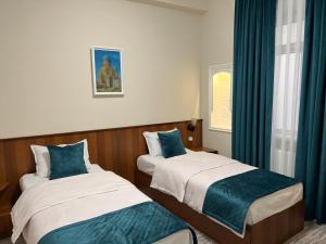 撒马尔罕Hotel Shakhname的配有蓝色窗帘的客房内的两张床