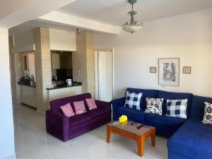 阿莱曼Chalet Marina Alamein first row sea view 3 bedroom-North Coast的客厅配有两张紫色沙发和一张桌子