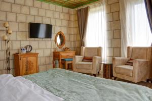 内夫谢希尔IVY Cappadocia的一间卧室配有一张床、两把椅子和电视