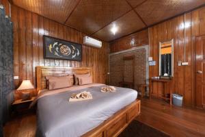 南邦Kanecha's Home Lampang的一间卧室配有一张带木墙的大床