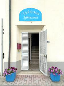 毕博纳的码头Affittacamere I Gigli di Mare的白色的建筑,有两盆蓝色的花