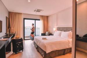 岘港Danang Bay View Apartment - Phòng Code chủ的一位女士站在酒店带床的房间