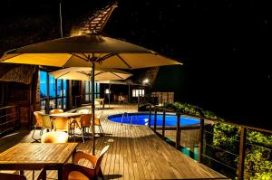 Massinga玛辛加海滩山林小屋的一个带桌子和遮阳伞的甲板和一个游泳池