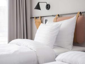 塔林Oru Hub Hotel Tallinn - Handwritten Collection的一张带白色枕头的床和一盏灯