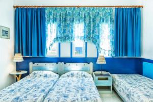 波塞蒂Xenios Faros Apartments的卧室设有两张床铺,拥有蓝色的墙壁和窗户