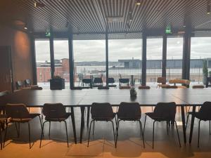 坦佩雷UNITY Tampere Trikootehdas的配有大窗户的客房内的大桌子和椅子