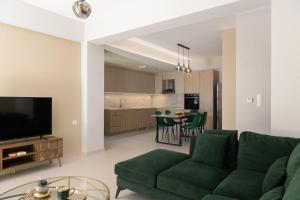 马鲁拉斯Mela Luxury Apartments的一间带绿色沙发的客厅和一间厨房