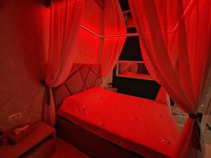 布加勒斯特XMX Jacuzzi and Baldachin Studio的红色的床和红色窗帘