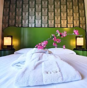 帕尔马Hotel Verdi Boutique Hotel的一张带白色毯子和粉红色鲜花的床