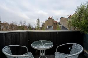 伦敦Award Winning 2 Bedroom House, King's Cross的阳台的天井配有2把椅子和1张桌子