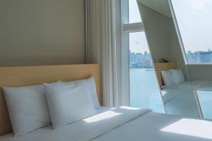 釜山Hotel Marine view的窗户客房内的一张带白色枕头的床