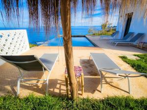 丹吉尔Très belle villa avec piscine et vue incroyable sur mediterannée (DAR NAIM)的游泳池旁的几把椅子和一张桌子