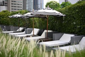 曼谷曼谷素坤逸 15 号瑞享酒店的庭院里摆放着一排椅子和遮阳伞