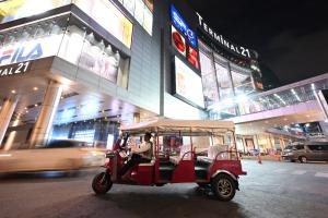 曼谷曼谷素坤逸 15 号瑞享酒店的一辆红色的高尔夫球车在晚上驶向城市街道