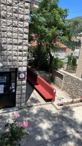 杜布罗夫尼克HI Hostel Dubrovnik的石屋外的红色长凳