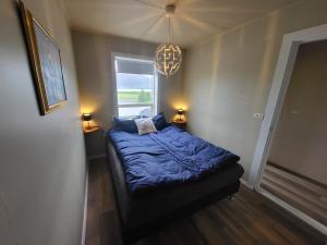 HríseyÁsgarður的一间卧室配有一张带蓝色棉被的床和窗户。