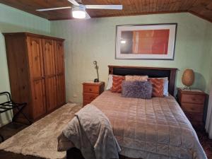 塔南达Little Para Cottage Tanunda的一间卧室配有一张大床和木制橱柜。