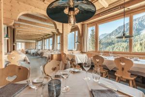 阿罗萨Hotel Alpensonne - Panoramazimmer & Restaurant的餐厅设有白色的桌椅和窗户。