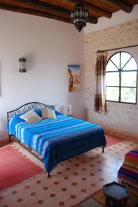 索维拉Riad Titima Essaouira的一间卧室配有一张带蓝色棉被的床和窗户。