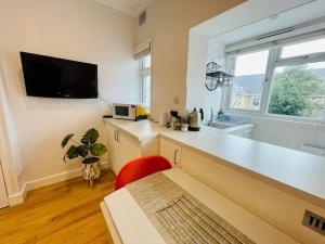 滨海绍森德NEW modernised flat in the heart of Leigh on Sea的厨房配有白色的柜台和红色的椅子