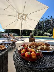 阿维尼翁Villa Pauline的桌子上一篮水果和面包,带雨伞