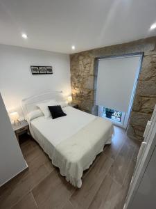 维拉加尔西亚·德·阿劳萨Casa Xoana的一间卧室设有一张大床和石墙