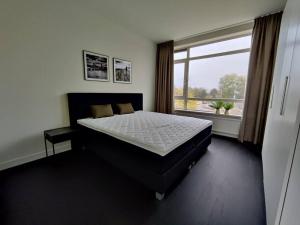 埃因霍温k50159 Spacious and modern apartment near the city center, free parking的一间卧室设有一张大床和一个大窗户