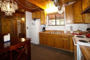 方斯金Canyon Cabin - A quaint cabin in a peaceful location yet close to Big Bear's attractions!的厨房配有木制橱柜和白色冰箱。