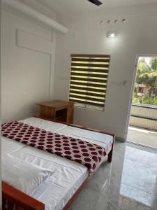 KotamangalamNew star homes的一间卧室配有一张床、一张桌子和一个窗户。