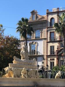 塞维利亚Hotel Tayko Sevilla的一座有雕像的建筑前的喷泉