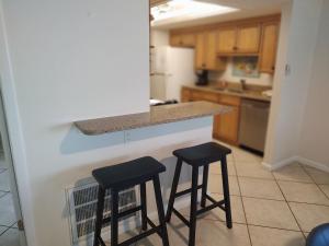 西耶斯塔岛Island House Beach Resort 2S的厨房在柜台上设有两个黑凳子