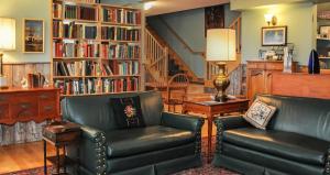 巴德克Chanterelle Inn & cottages的客厅配有两把椅子和书架
