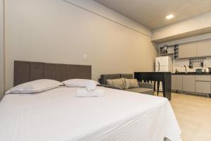 阿雷格里港Studio Residencial 4º Distrito的一间带白色床的卧室和一间厨房