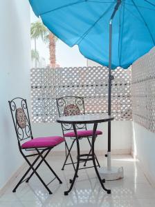 塞拉Your Airport Oasis Resort 15 Minutes from Rabat的蓝色伞下的一张桌子和两把椅子