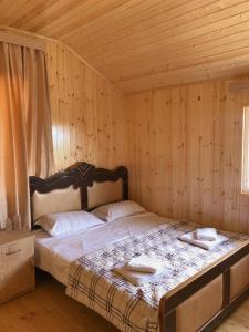 GordiHotel Okatsia სასტუმრო ოკაცია的木制客房内的一间卧室,配有一张床