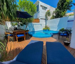 坎昆Villa Sofía Holiday Accommodation的一个带蓝色游泳池、桌子和椅子的庭院